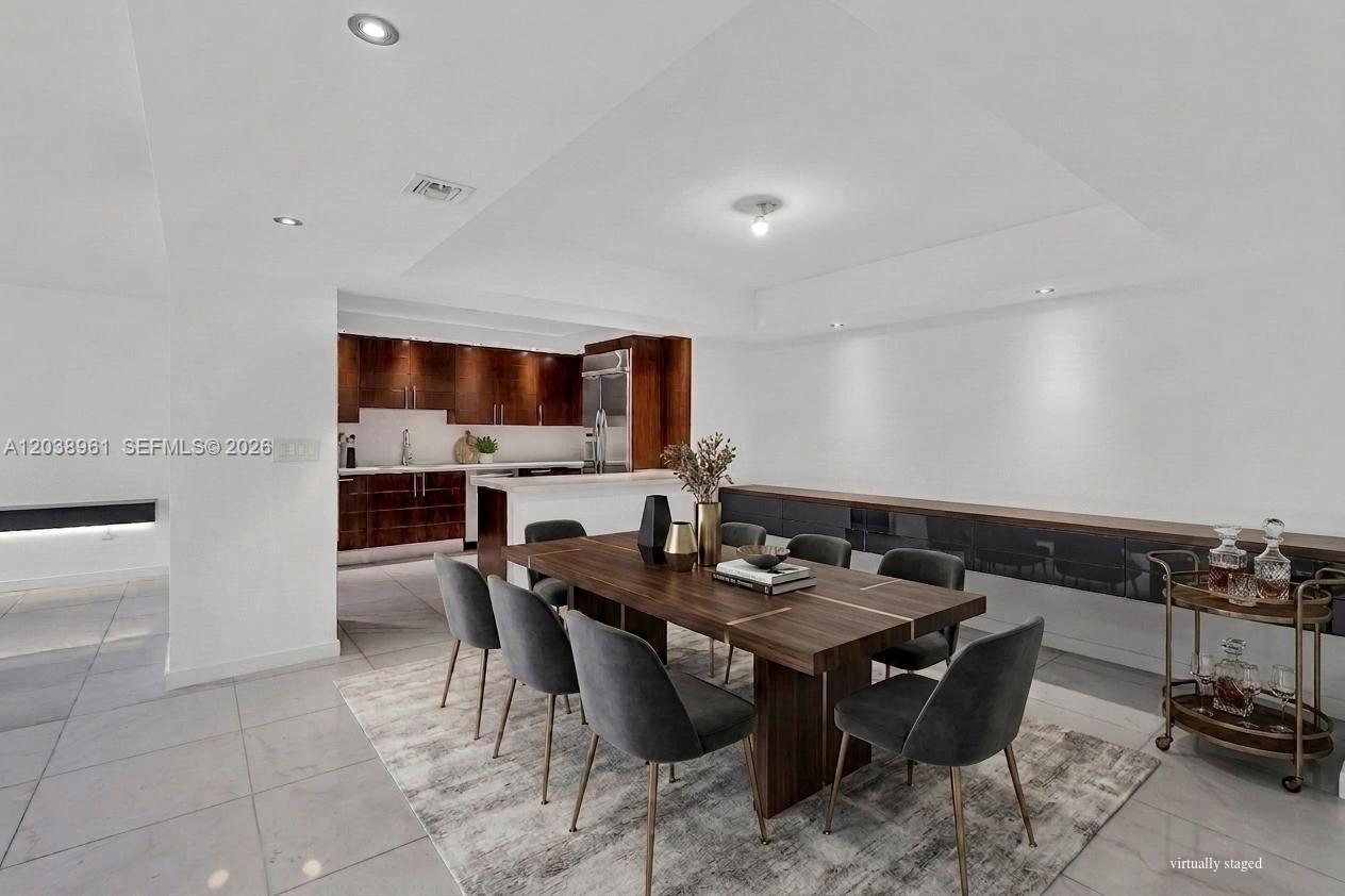 A dining area features a wooden table with grey chairs and a dark sideboard — 2 Grove Isle Dr # B205, Miami FL 33133, MIAMI, FL