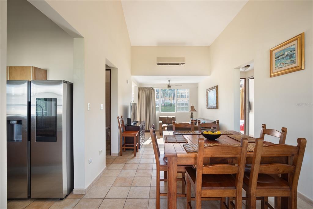 A dining area with a wooden table and chairs leads into a living room beyond — 1 COSTA DORADA UNIT B303, RIO GRANDE, PR