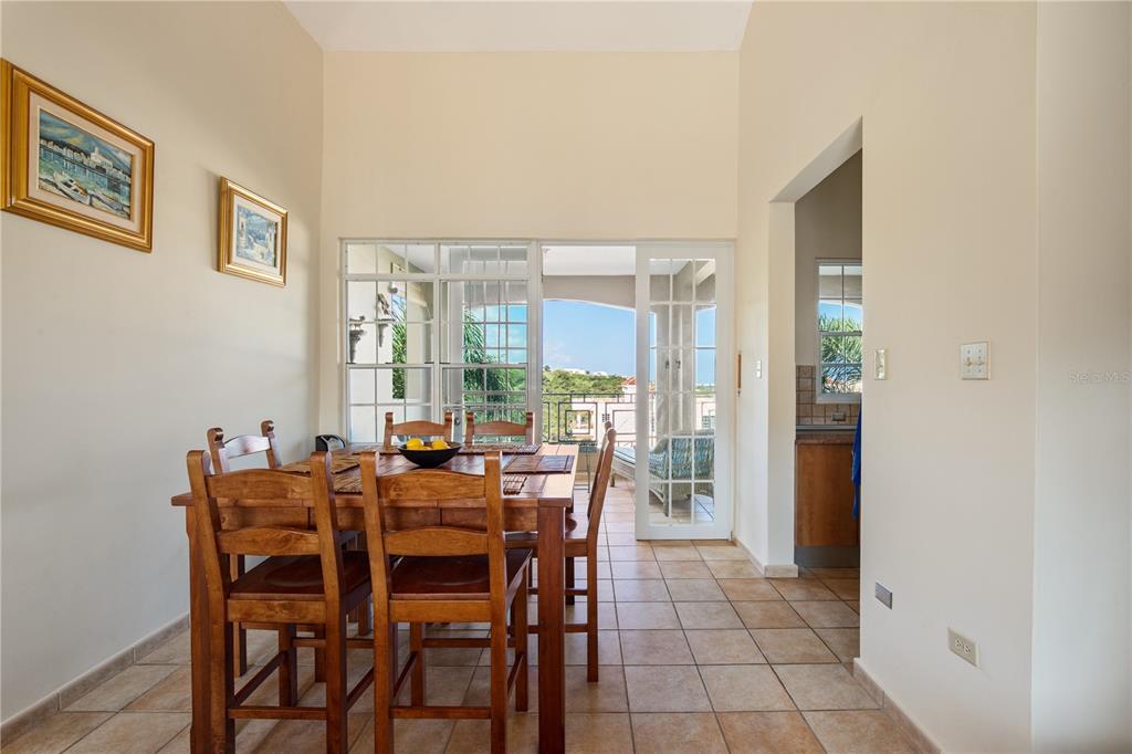 A dining room with a wooden table and chairs, tile floors, and a balcony view — 1 COSTA DORADA UNIT B303, RIO GRANDE, PR