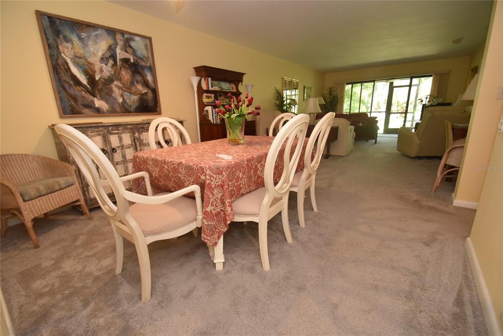 A dining area with a patterned tablecloth, white chairs, and a large painting on the wall — 1516 PELICAN COVE ROAD UNIT GR144, SARASOTA, FL