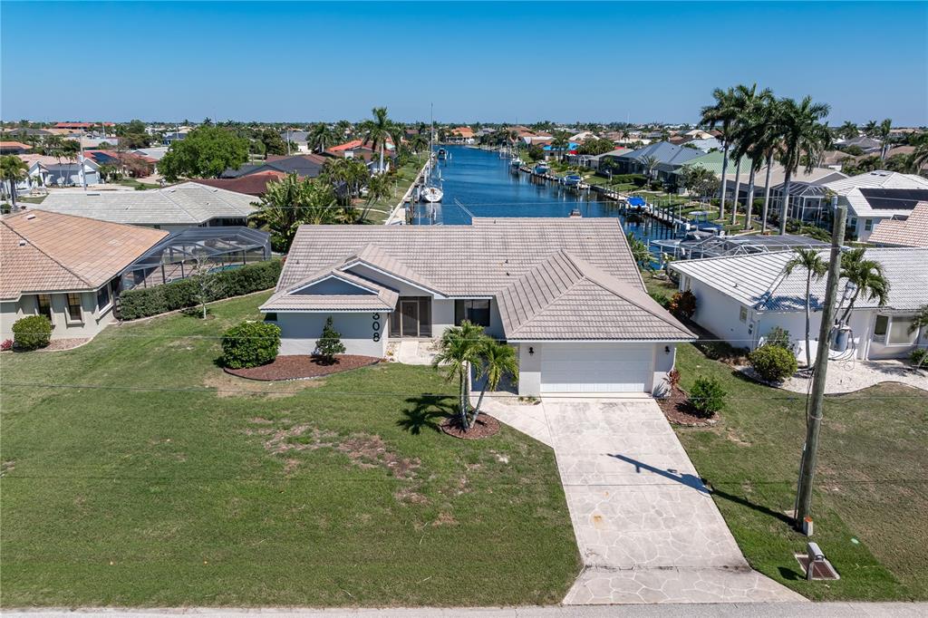 An aerial view shows a single-story house with a tiled roof and a canal backyard — 308 COLONY POINT DRIVE, PUNTA GORDA, FL