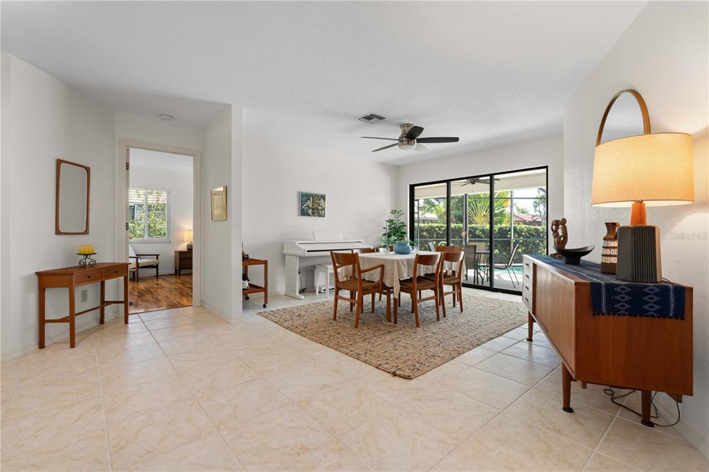 A dining area with a white piano sits adjacent to a living space with tile floors — 308 COLONY POINT DRIVE, PUNTA GORDA, FL