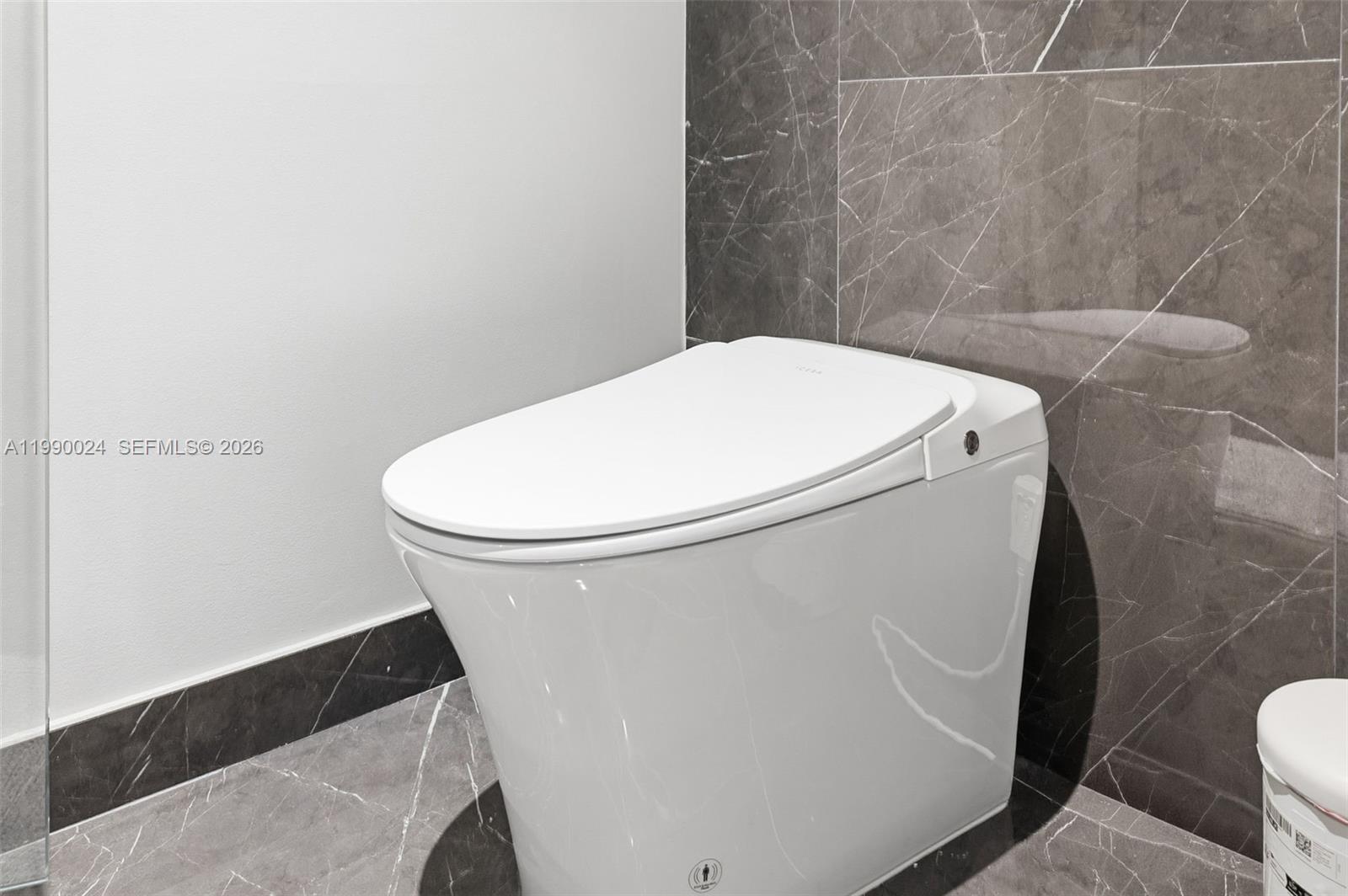 A white smart toilet is positioned against a wall with dark gray marble tiles — 20 NE 11th St # 2306A, Miami FL 33132, MIAMI, FL