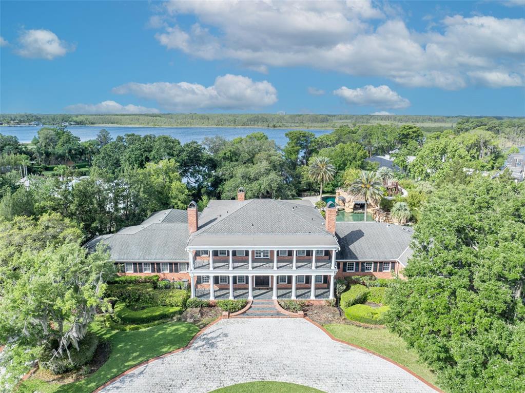 An aerial view shows a large brick house with a two-story porch facing a lake — 9726 KILGORE ROAD, ORLANDO, FL