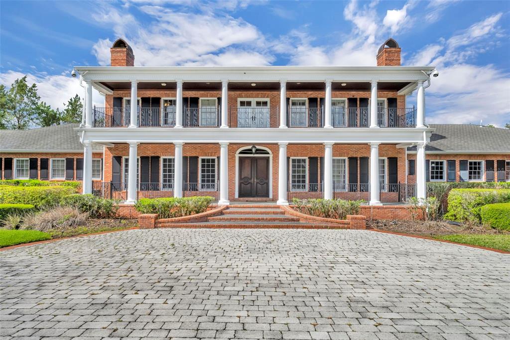 A two-story brick mansion with a large front porch, white columns, and a cobblestone driveway — 9726 KILGORE ROAD, ORLANDO, FL