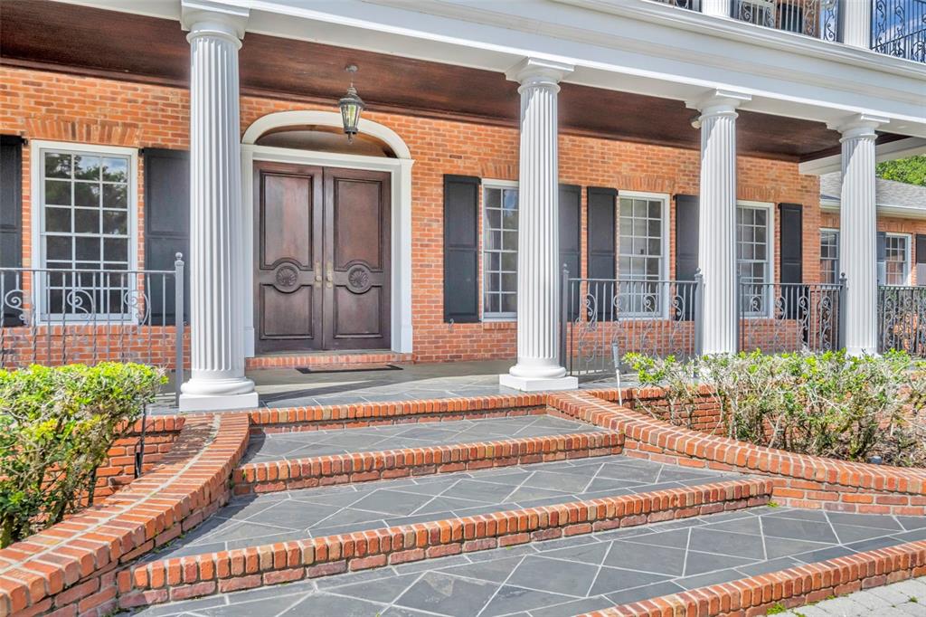 A brick house exterior features a covered porch with white columns and double wooden doors — 9726 KILGORE ROAD, ORLANDO, FL