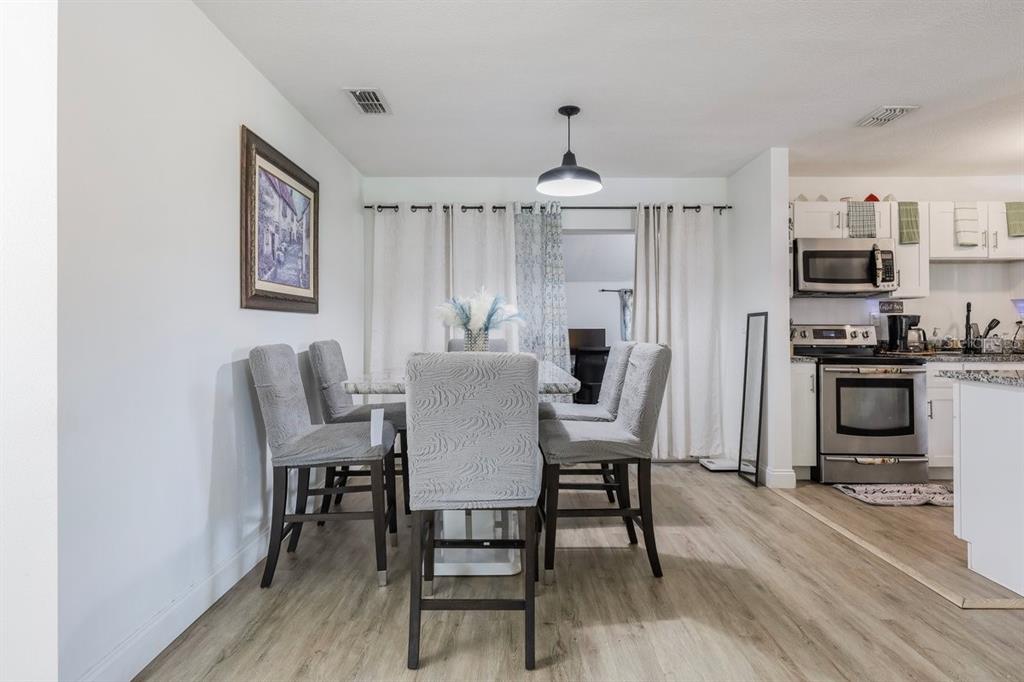 A dining area with a table and chairs sits adjacent to a white kitchen — 4725 CEPEDA STREET, ORLANDO, FL
