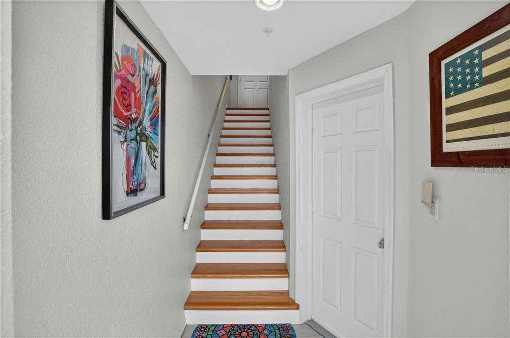 A staircase with wooden treads and white risers leads to a landing with a door — 1950 OREGON TRAIL UNIT 1A, ENGLEWOOD, FL