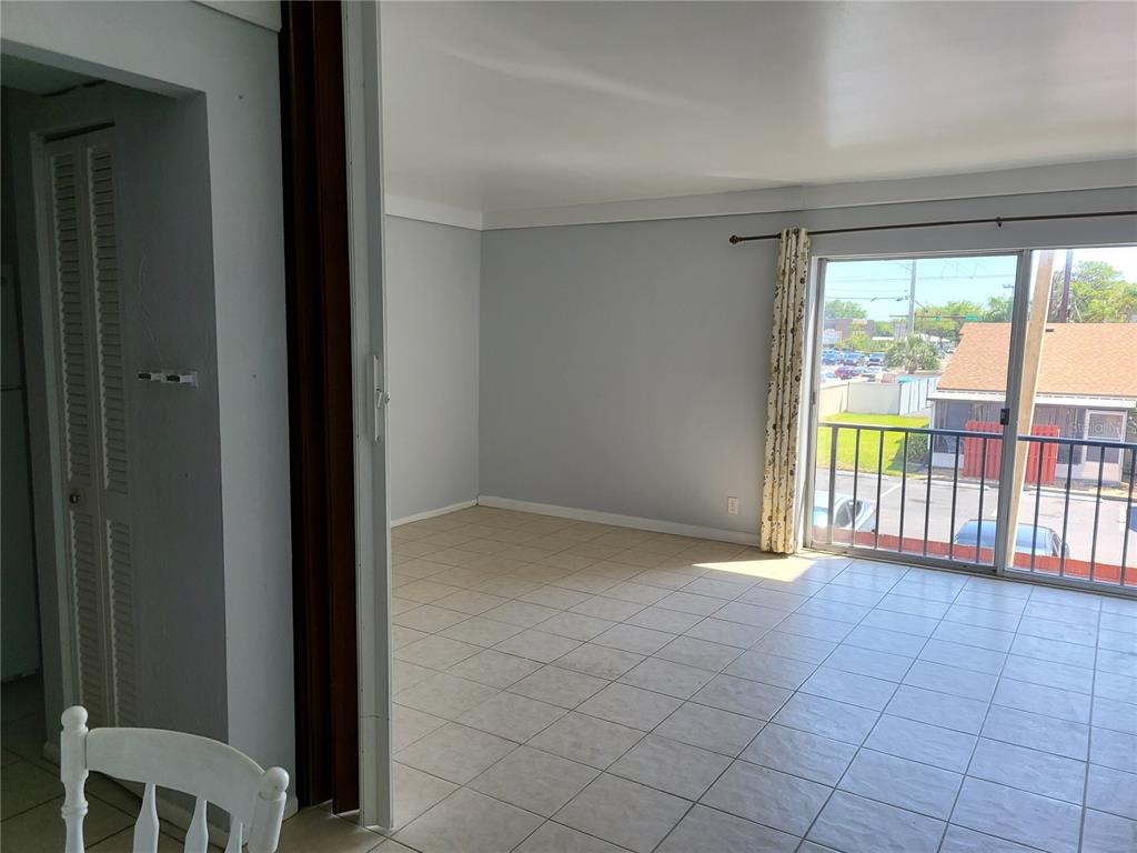 An interior view of a room with tiled floors, light gray walls, and a sliding door — 2763 WOODGATE LANE UNIT 207, SARASOTA, FL
