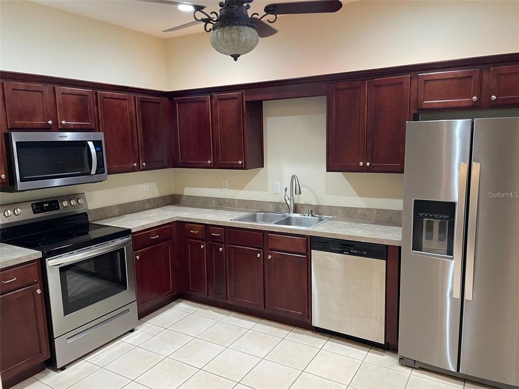 A kitchen featuring dark wood cabinets, stainless steel appliances, and light-colored tile flooring — 9035 VISTA VERDE DRIVE, PALMETTO, FL