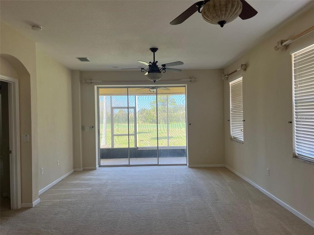 A carpeted living room features a ceiling fan, sliding glass doors, and a screened-in lanai — 9035 VISTA VERDE DRIVE, PALMETTO, FL