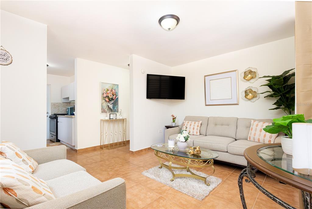 A living room features tile floors, a beige sofa, a glass coffee table, and a television — 339 ST BO MONTOSO UNIT 145, MAYAGUEZ, PR