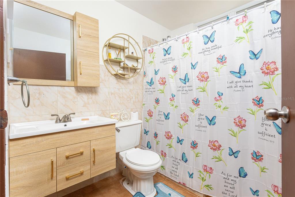 A bathroom features a light wood vanity, a round wall shelf, and a butterfly-patterned shower curtain — 339 ST BO MONTOSO UNIT 145, MAYAGUEZ, PR