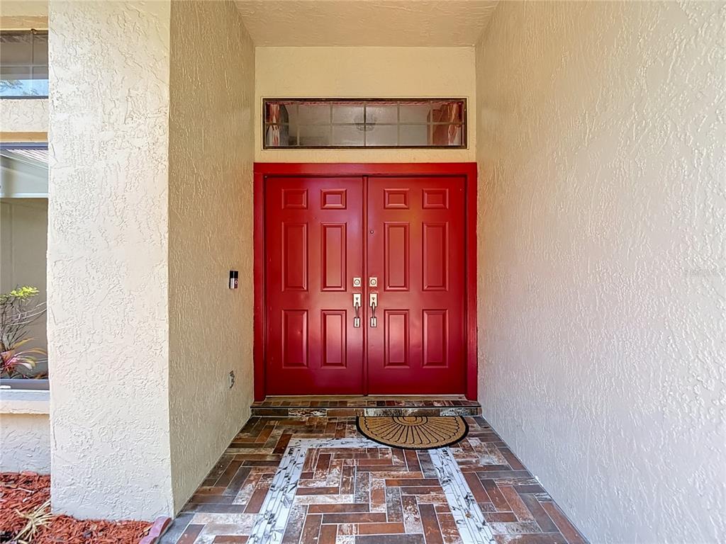 A red double front door with a transom window sits above a tiled entryway — 16040 PENWOOD DRIVE, TAMPA, FL