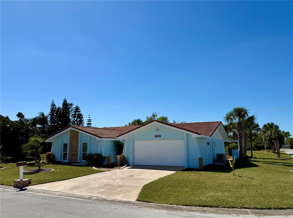 A light blue, single-story house with a two-car garage and a tiled roof — 9801 SAN MORENO WAY, PORT RICHEY, FL
