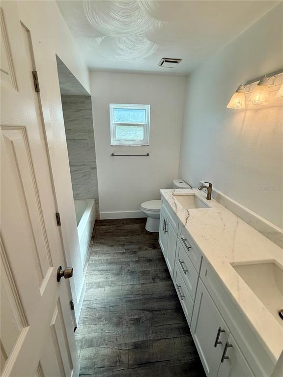 A bathroom features a white vanity with a marble countertop, a toilet, and a tub — 9801 SAN MORENO WAY, PORT RICHEY, FL