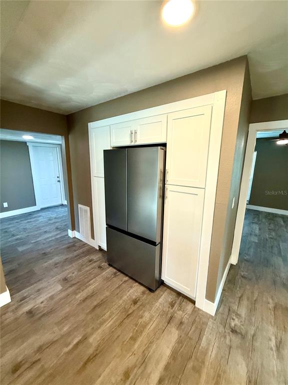 A stainless steel refrigerator is built into white cabinetry in a room with wood-look flooring — 9801 SAN MORENO WAY, PORT RICHEY, FL
