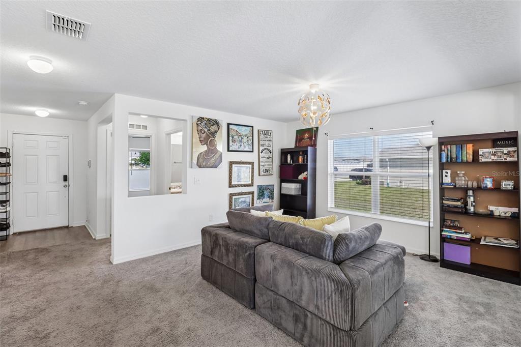 A living room features gray carpet, a sectional sofa, a bookshelf, and a large window — 2082 FICUS STREET, MASCOTTE, FL