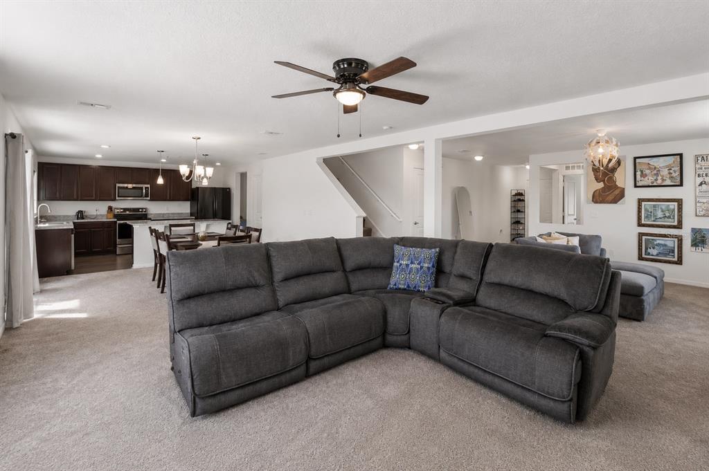 A spacious living room with a gray sectional sofa opens into a kitchen and dining area — 2082 FICUS STREET, MASCOTTE, FL