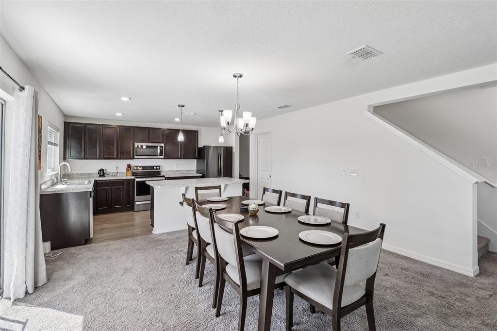 A dining area with a dark wood table and chairs sits adjacent to a kitchen — 2082 FICUS STREET, MASCOTTE, FL