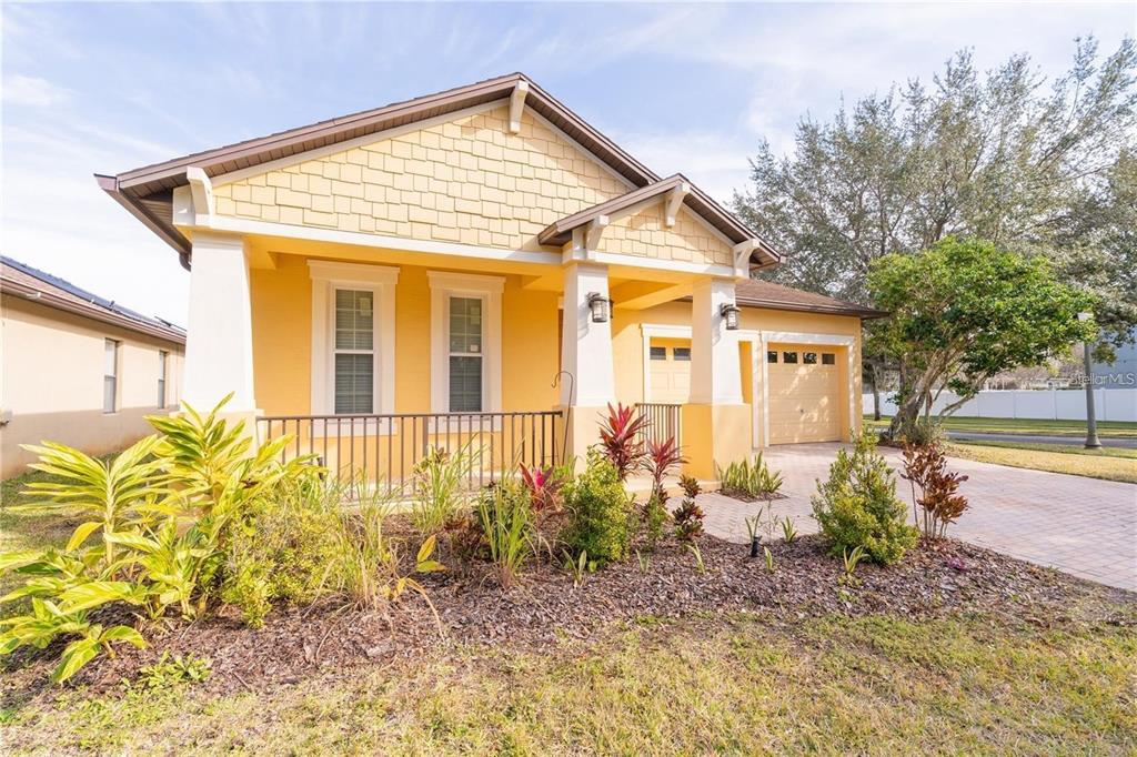 A yellow single-story house with a front porch, garage, and landscaped yard — 9763 MOSS ROSE WAY, ORLANDO, FL