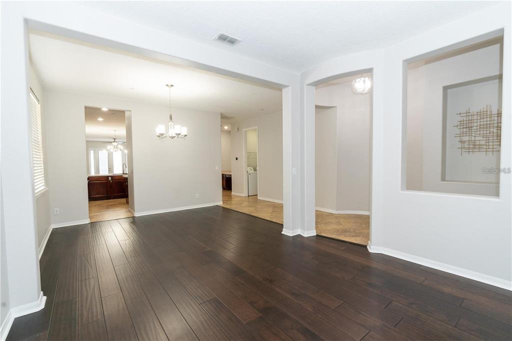 A dining area with dark wood floors leads to a kitchen and tiled hallway — 9763 MOSS ROSE WAY, ORLANDO, FL