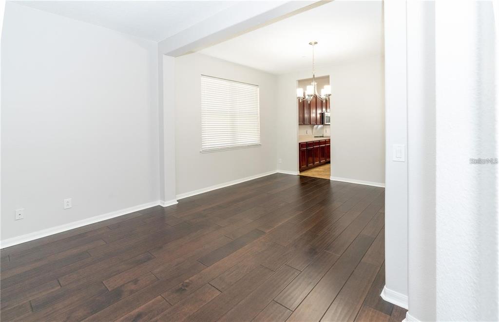 A dining room with dark wood floors and a view into a kitchen — 9763 MOSS ROSE WAY, ORLANDO, FL