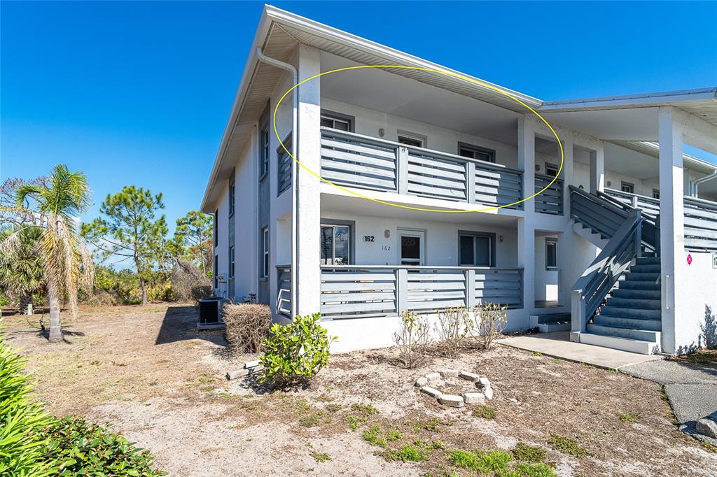 The exterior of a two-story building features a second-floor balcony with horizontal wood railings — 6800 PLACIDA ROAD UNIT 262, ENGLEWOOD, FL
