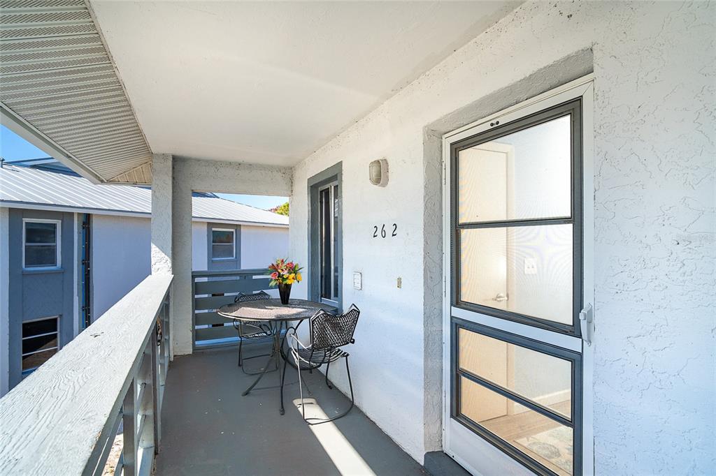 A covered balcony features a small metal bistro set and a screen door entrance — 6800 PLACIDA ROAD UNIT 262, ENGLEWOOD, FL