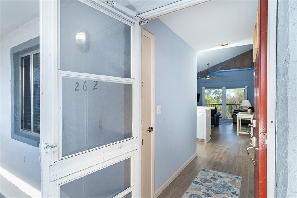 An open red front door reveals a view into a home with light blue walls — 6800 PLACIDA ROAD UNIT 262, ENGLEWOOD, FL