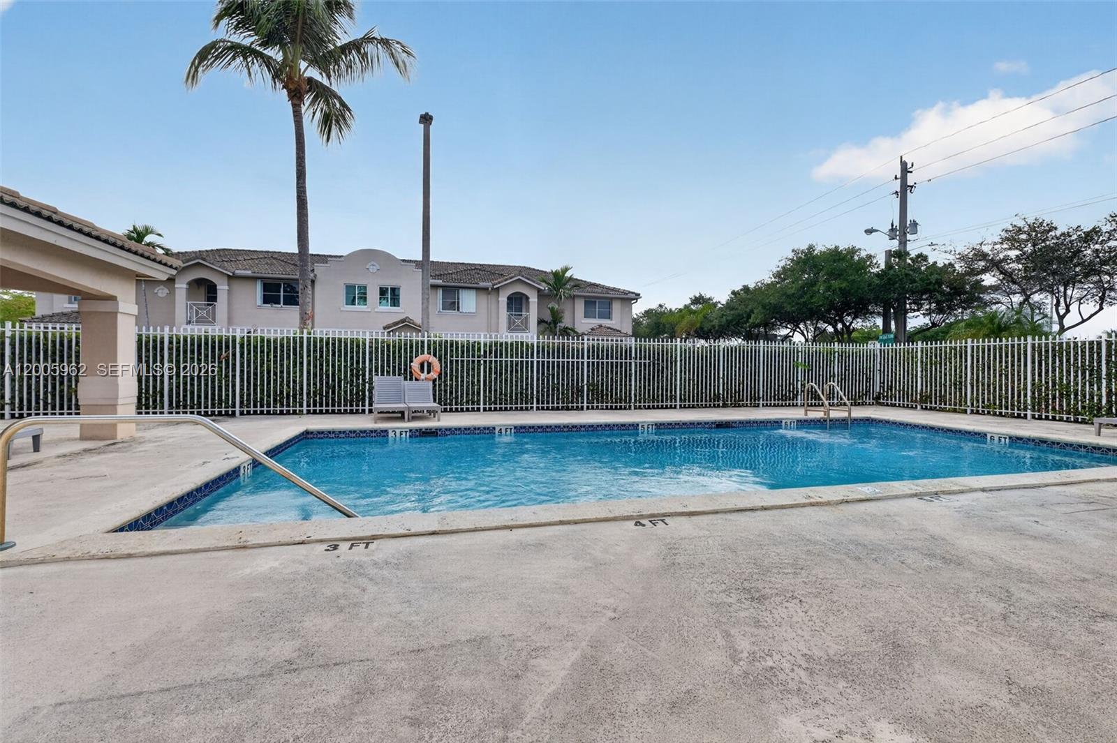 A rectangular swimming pool with depth markers sits in front of a white fence and buildings — 16624 NW 73rd Ct # 16624, Miami Lakes FL 33014, MIAMI LAKES, FL