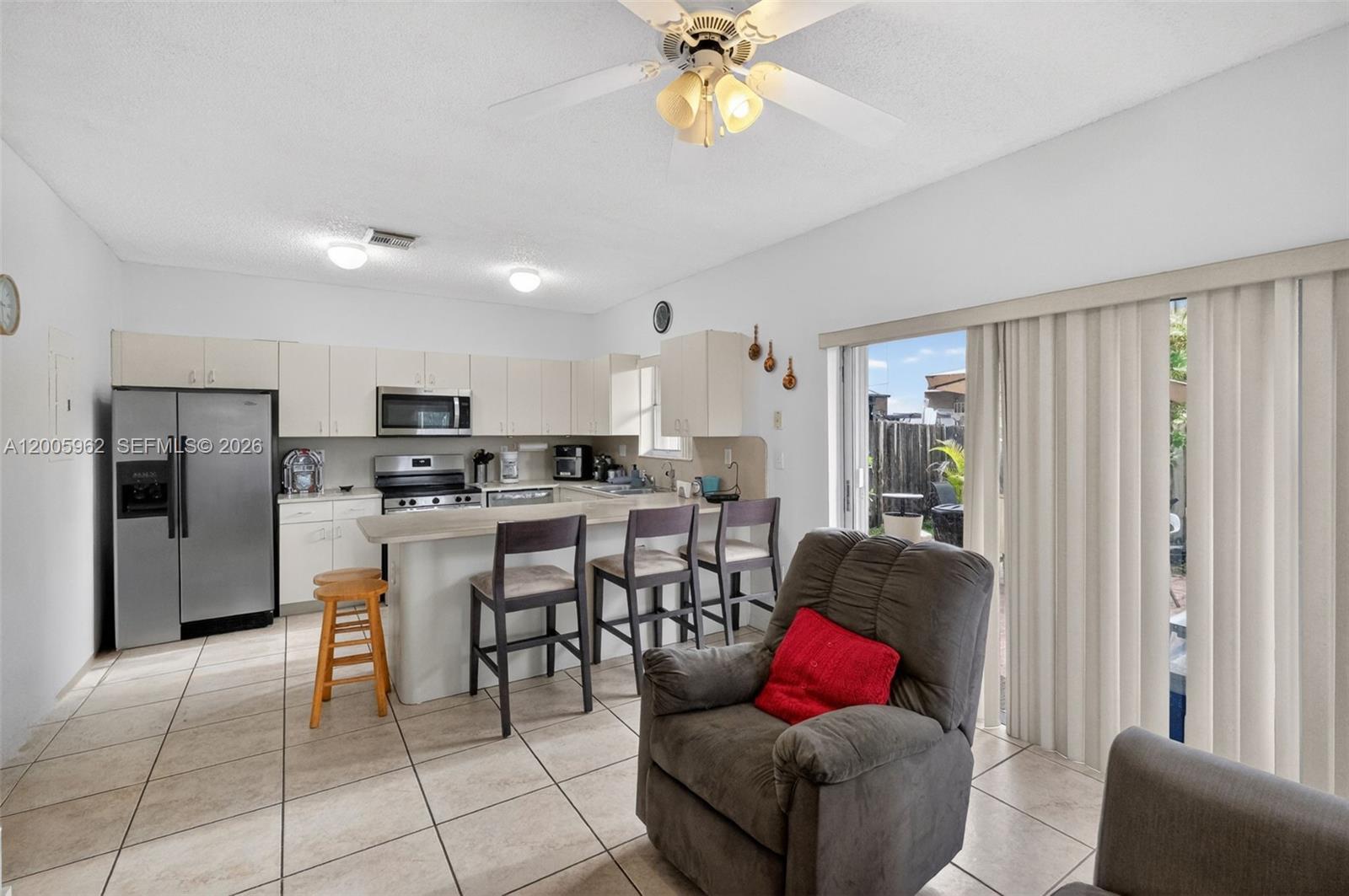 A kitchen with white cabinets and a breakfast bar opens to a living area — 16624 NW 73rd Ct # 16624, Miami Lakes FL 33014, MIAMI LAKES, FL
