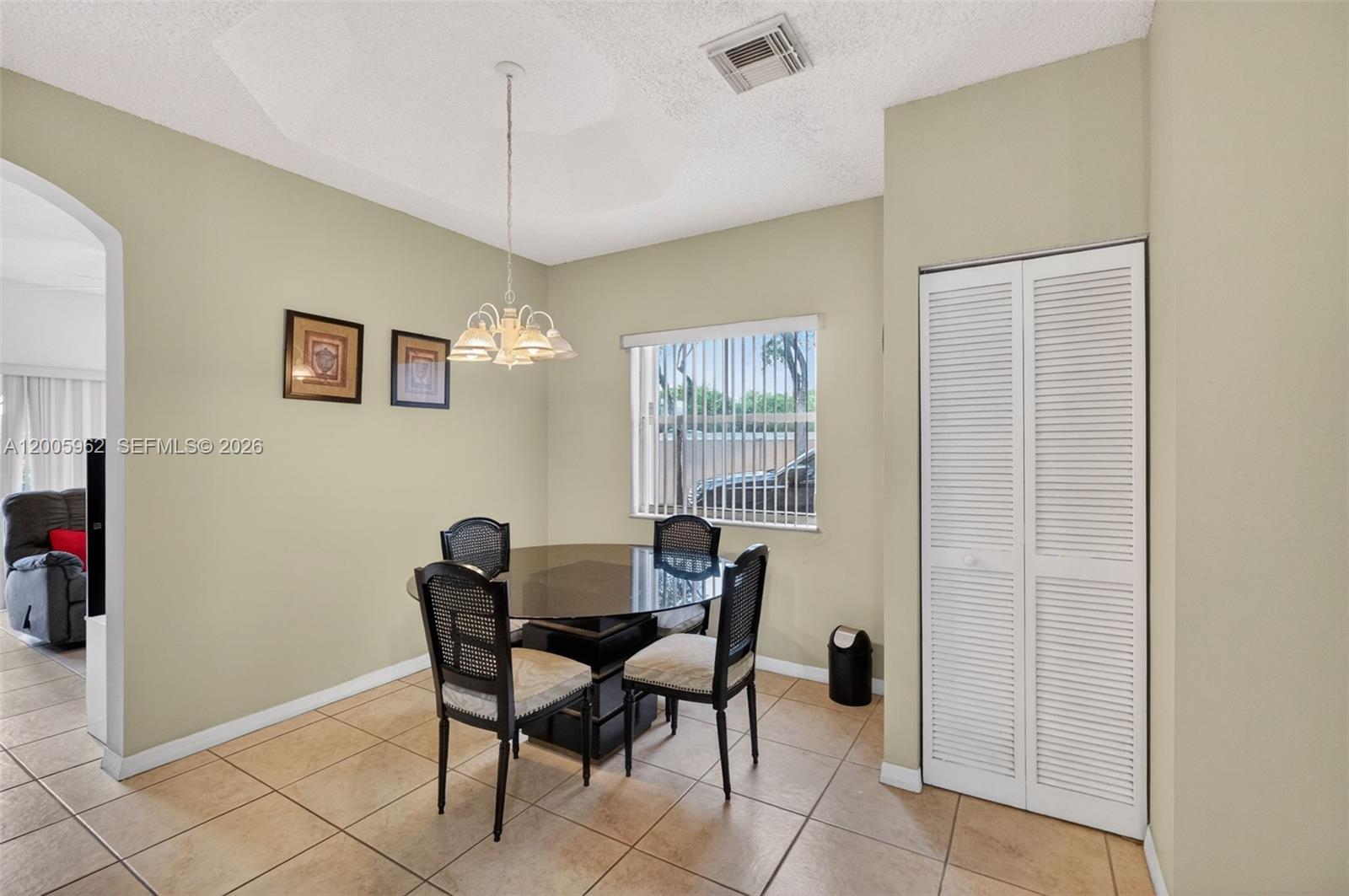A dining area features a glass-topped table, four chairs, a chandelier, and tile flooring — 16624 NW 73rd Ct # 16624, Miami Lakes FL 33014, MIAMI LAKES, FL