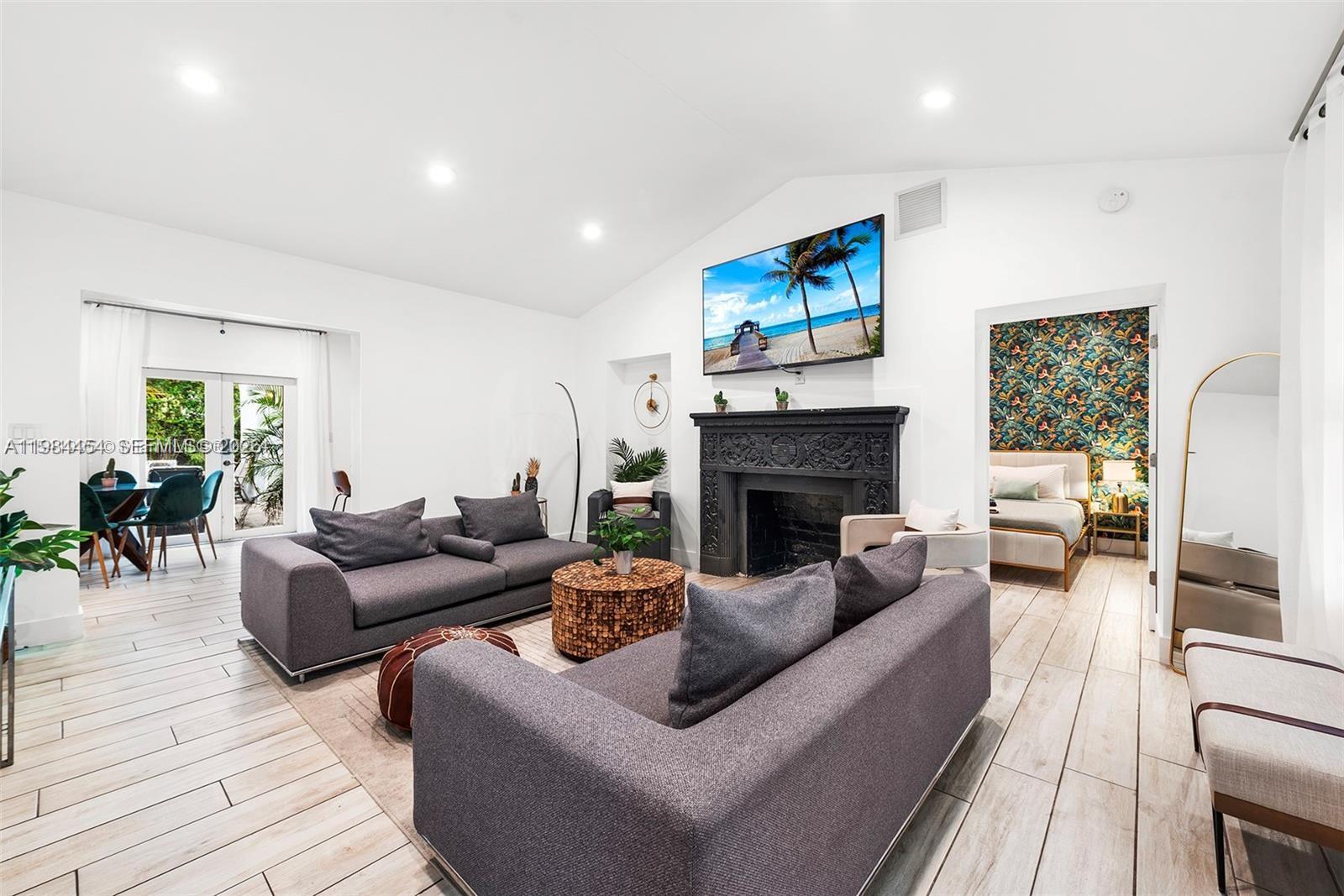 A living room features a black fireplace, two grey sofas, and a view into a bedroom — 232 NW 59th St, Miami FL 33127, MIAMI, FL