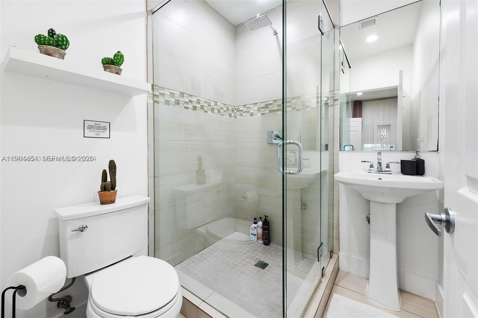 A small bathroom features a glass-enclosed shower, a pedestal sink, and a white toilet — 232 NW 59th St, Miami FL 33127, MIAMI, FL
