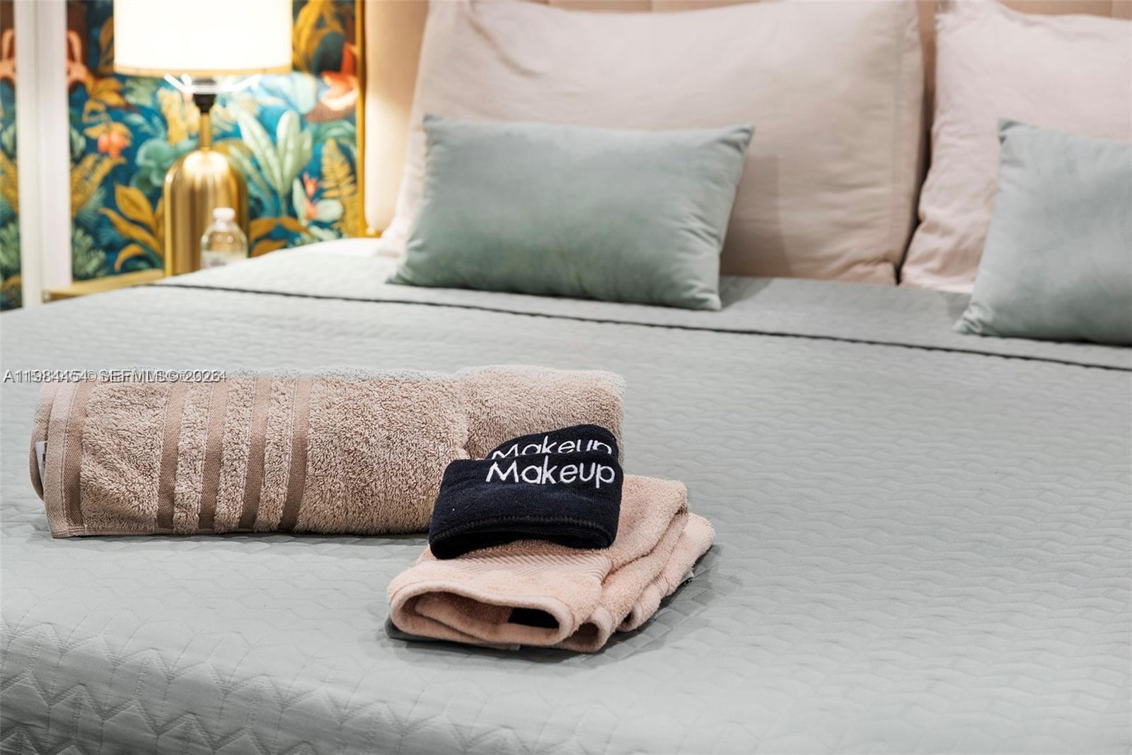 A bed is made with a light green quilt, pillows, and folded towels — 232 NW 59th St, Miami FL 33127, MIAMI, FL