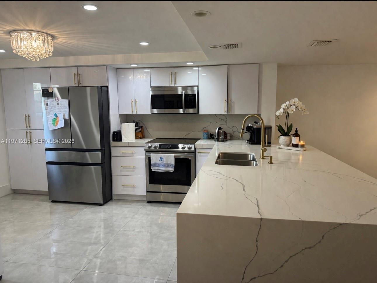 A modern kitchen features white cabinetry, stainless steel appliances, and a large marble-topped island — 2308 NE 7th St # 29, Hallandale Beach FL 33009, HALLANDALE BEACH, FL