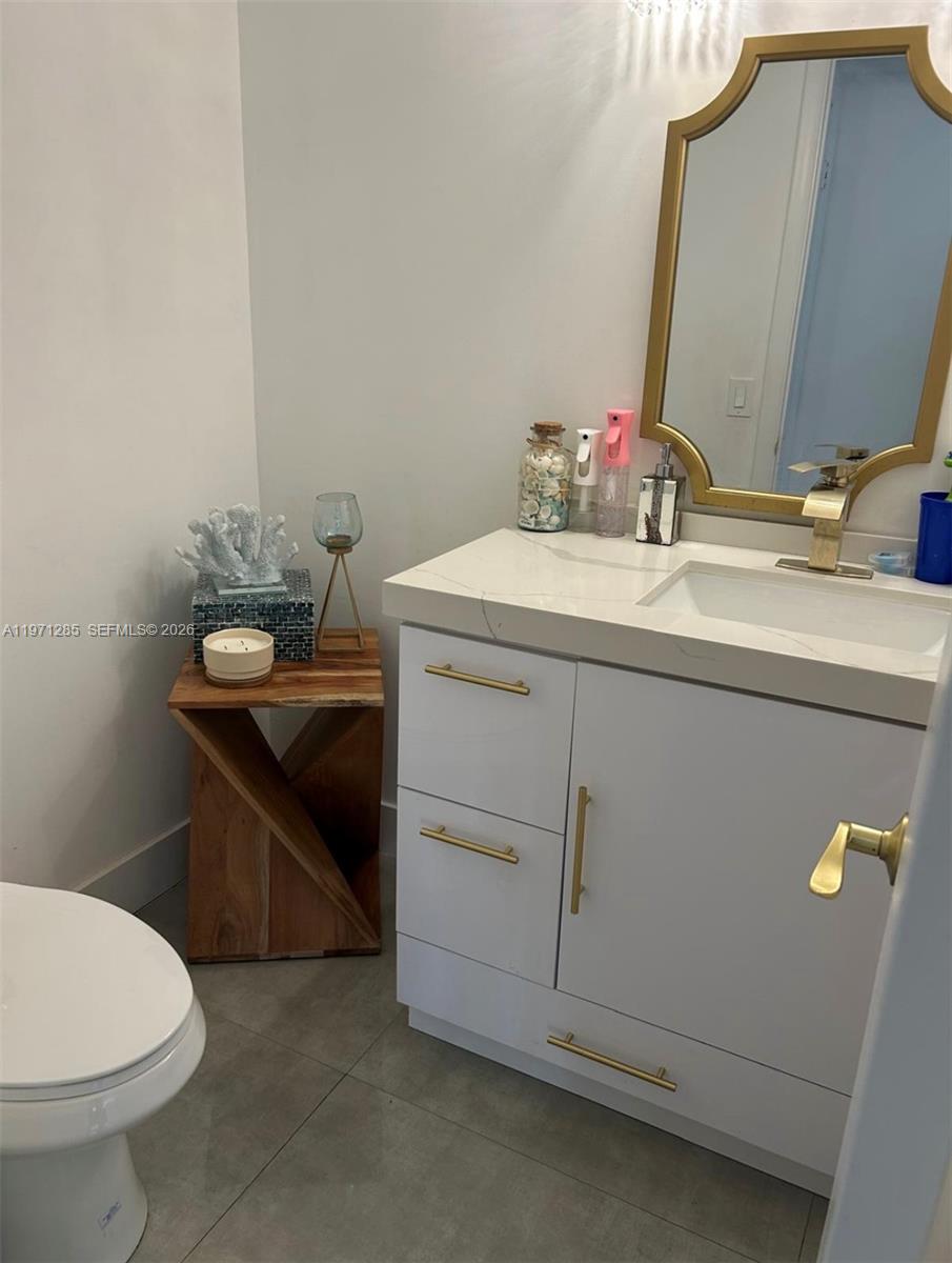A bathroom features a white vanity with gold hardware, a gold-framed mirror, and a wooden side table — 2308 NE 7th St # 29, Hallandale Beach FL 33009, HALLANDALE BEACH, FL