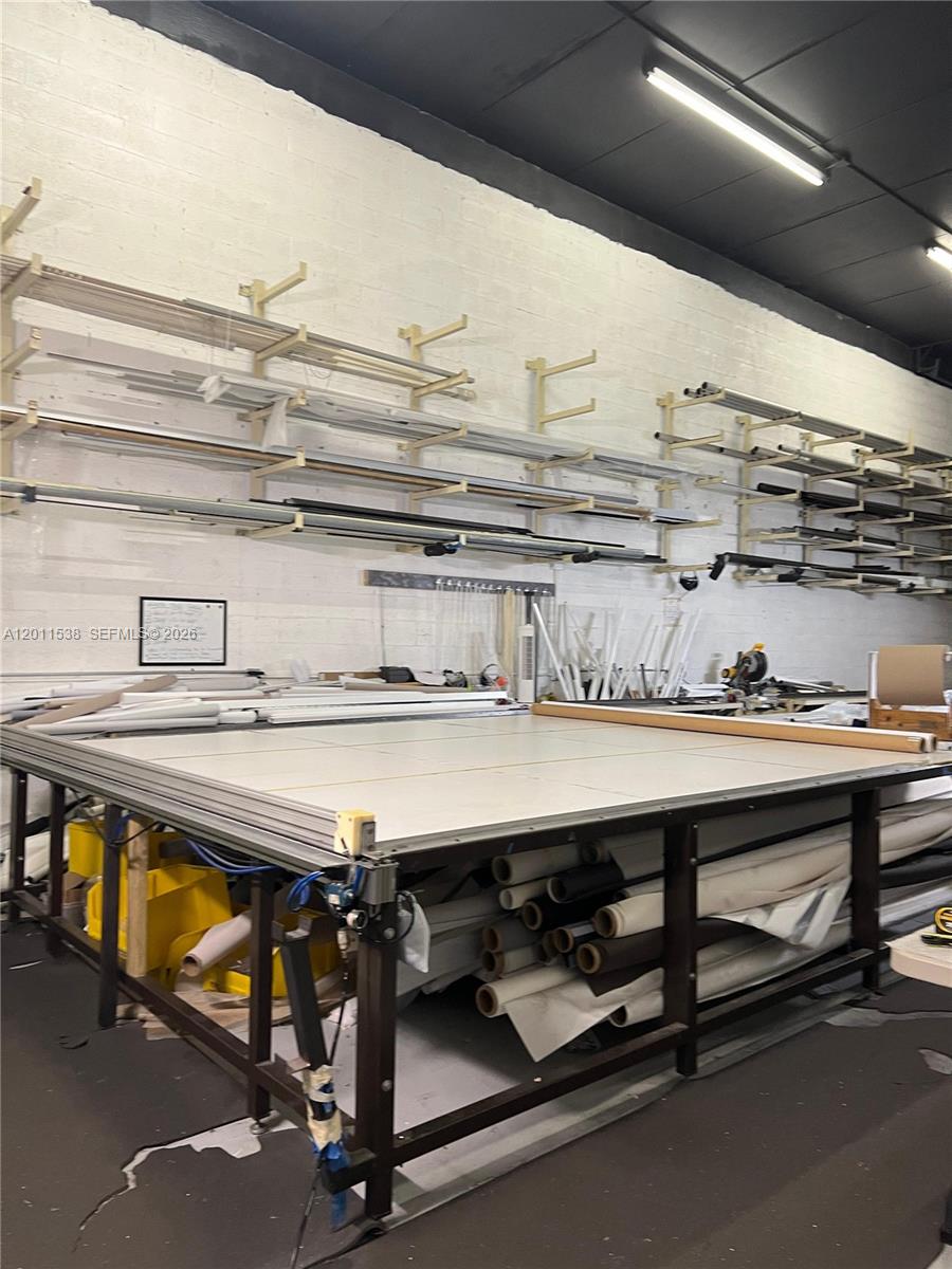 A workshop features a large cutting table, wall-mounted storage racks, and rolls of material — 13210 SW 132nd Ave, Miami FL 33186, MIAMI, FL