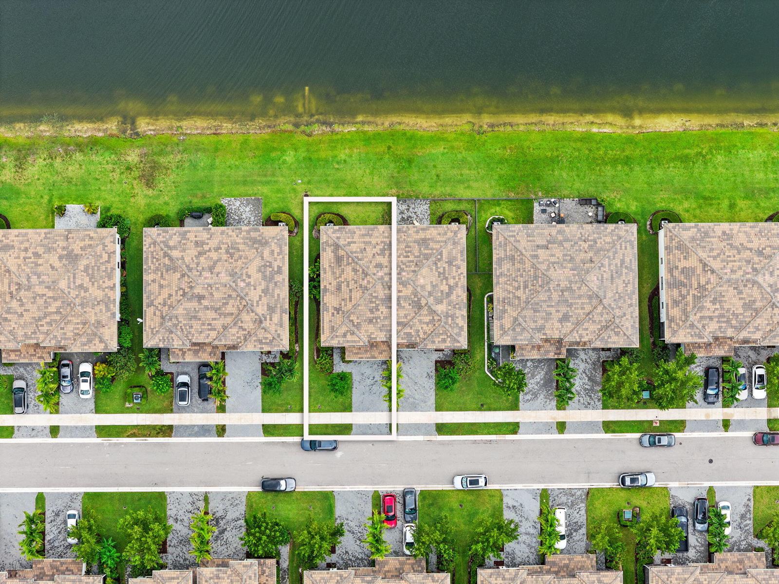 An aerial view shows a row of houses with tiled roofs situated along a lakefront — 8697 Corvus, Lake Worth FL 33467, LAKE WORTH, FL