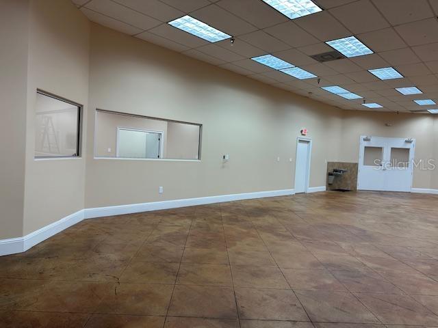 An empty commercial room features tan walls, a stained concrete floor, and drop ceiling lights — 350 ANCHOR ROAD UNIT 1050, CASSELBERRY, FL