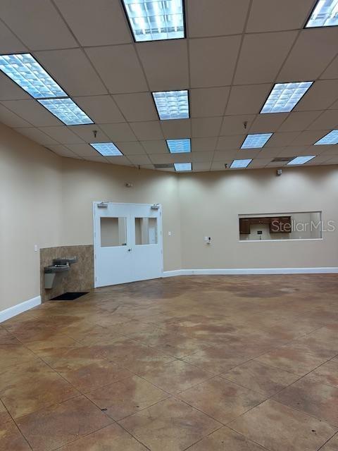 An empty commercial room features a stained concrete floor, drop ceiling, and a double door — 350 ANCHOR ROAD UNIT 1050, CASSELBERRY, FL