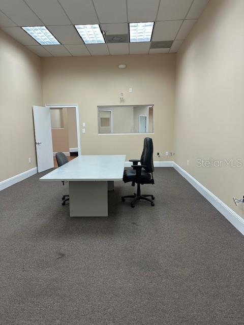 An office room features a white desk, two chairs, beige walls, and a rectangular window — 350 ANCHOR ROAD UNIT 1050, CASSELBERRY, FL