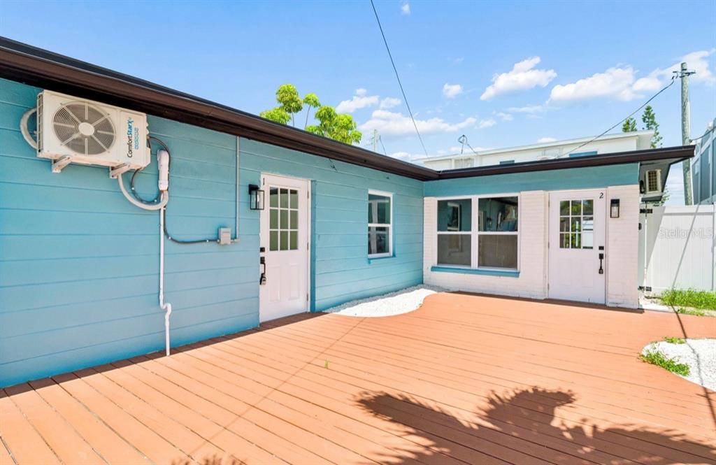 An exterior view of a blue house with a wooden deck and two white doors — 14906 N BAYSHORE DRIVE, MADEIRA BEACH, FL