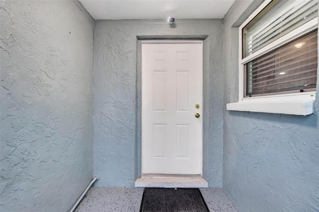 A white six-panel door is centered on a gray textured wall beside a window — 8700 58TH LANE N, PINELLAS PARK, FL