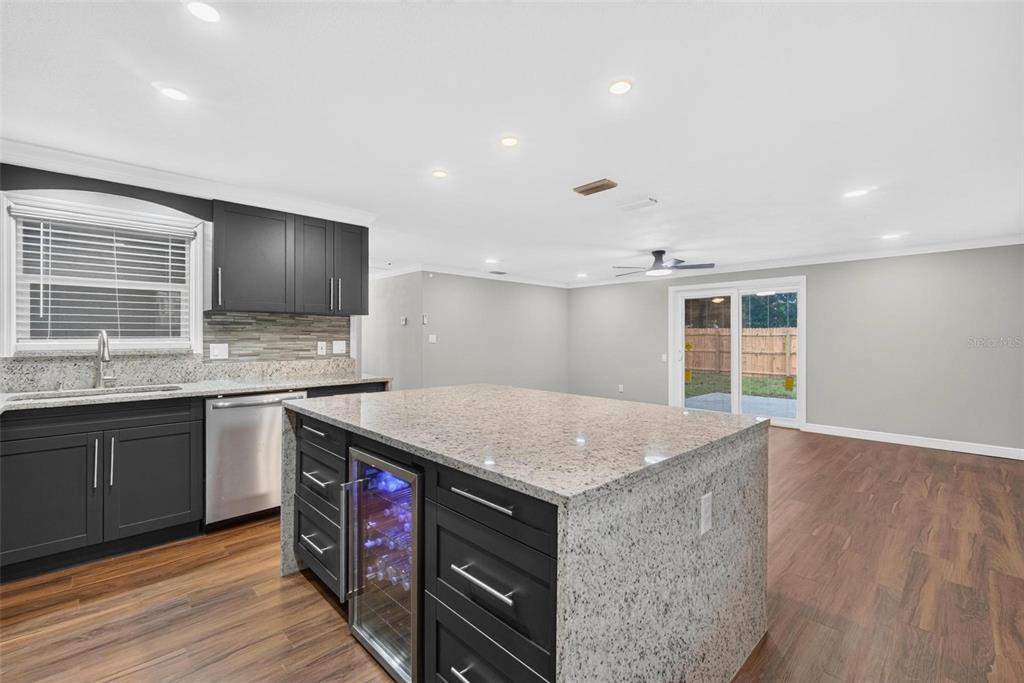 A kitchen with dark cabinets, granite countertops, a center island, and wood-look flooring — 8700 58TH LANE N, PINELLAS PARK, FL