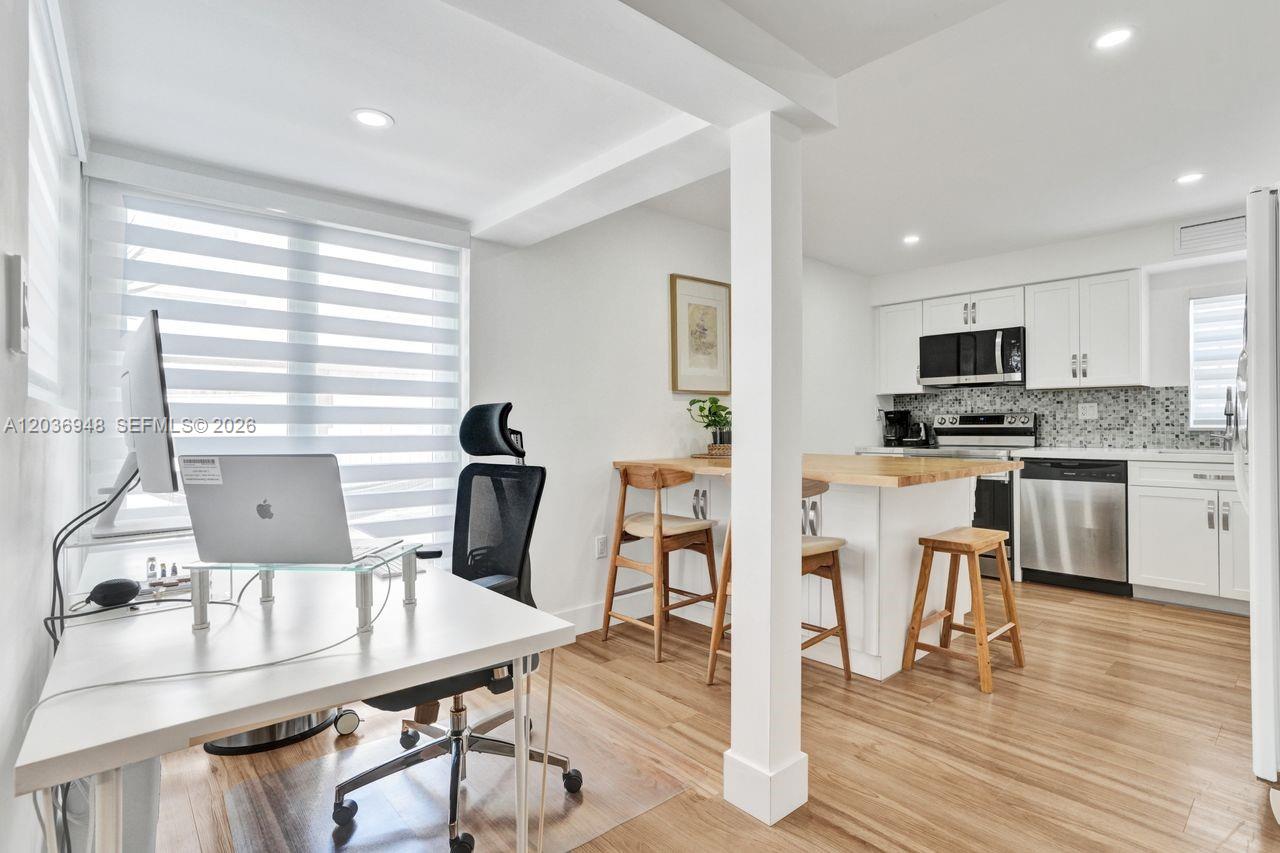 A home office area transitions into a kitchen with white cabinetry and a wooden island — 4555 SW 68th Ct Cir # 111, Miami FL 33155, MIAMI, FL