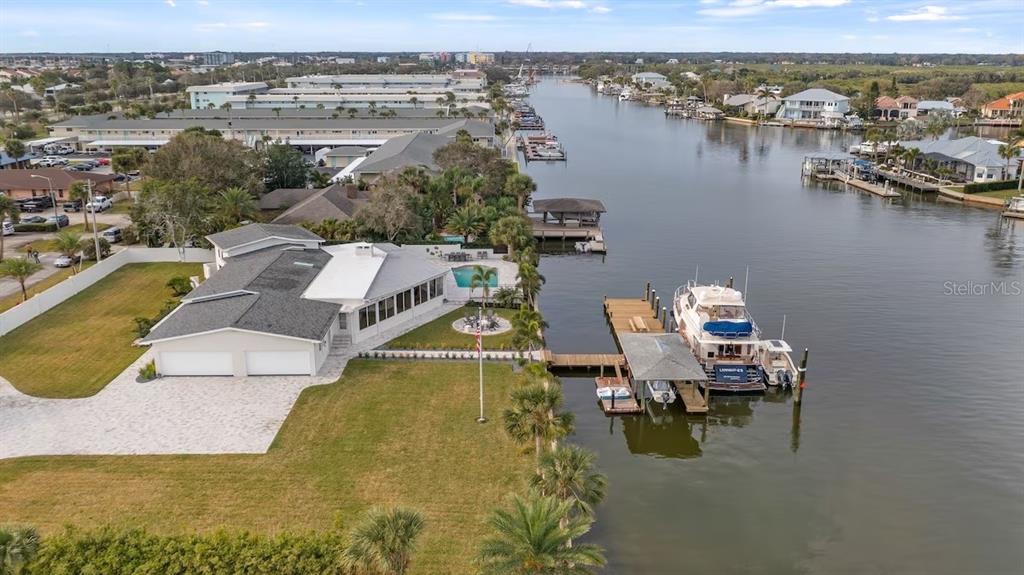 An aerial view shows a waterfront house with a pool, dock, and boat on a canal — 102 E CIRCLE DRIVE, NEW SMYRNA BEACH, FL