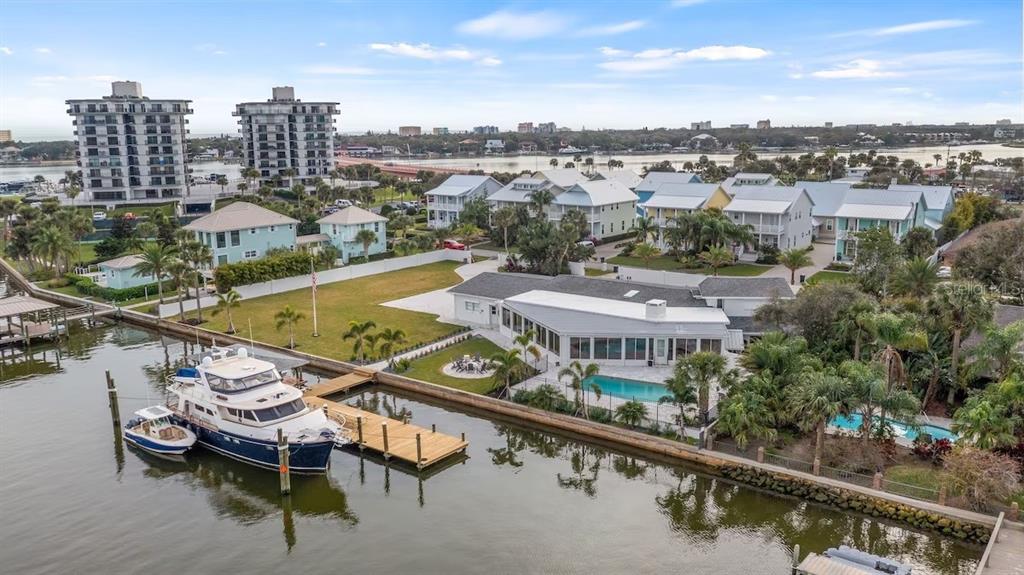 An aerial view shows a waterfront home with a pool, dock, and large boat — 102 E CIRCLE DRIVE, NEW SMYRNA BEACH, FL