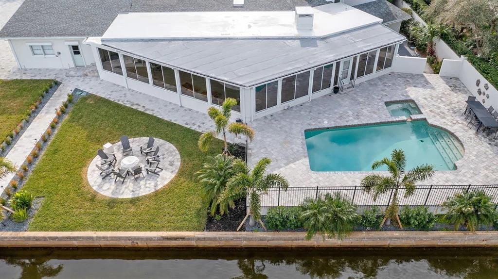 An aerial view shows a house with a sunroom, swimming pool, and patio by water — 102 E CIRCLE DRIVE, NEW SMYRNA BEACH, FL